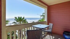 A balcony with a view of the ocean, a table, two chairs, and a potted plant. - Dawn 631 by Ryson Vacation Rentals (Galveston)
