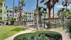 Un complexe hôtelier doté d’une piscine, de palmiers et d’une pelouse bien entretenue.