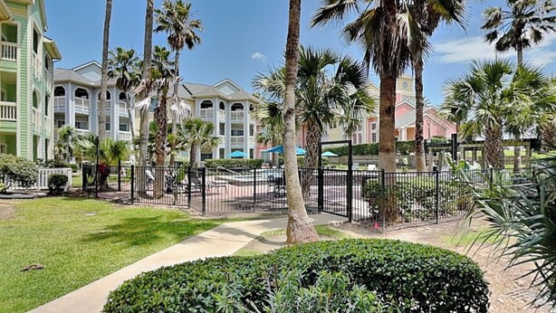 A resort with a pool area, palm trees, and a well-maintained lawn. - Oasis at the Dawn by Ryson Vacation Rentals (Galveston)