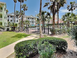 A resort with a pool area, palm trees, and a well-maintained lawn.