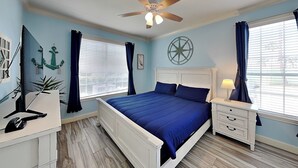 A bedroom with a bed, nightstand, desk, and a ceiling fan. - Oasis at the Dawn by Ryson Vacation Rentals (Galveston)