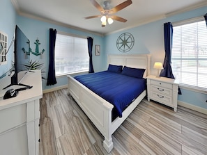 A bedroom with a bed, nightstand, desk, and a ceiling fan.