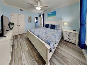 Un dormitorio con cama, mesita de noche, cómoda y ventilador de techo.