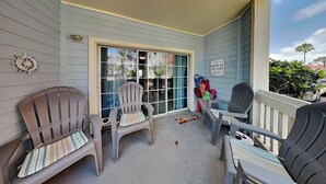 Une véranda couverte avec quatre fauteuils Adirondack, une grande porte-fenêtre coulissante et une pancarte sur laquelle on peut lire : « Oasis à l’aube ».