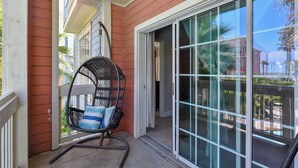 A porch with a rocking chair, a sliding glass door, and a view of the street. - Sea n' Swim by Ryson Vacation Rentals (Galveston)