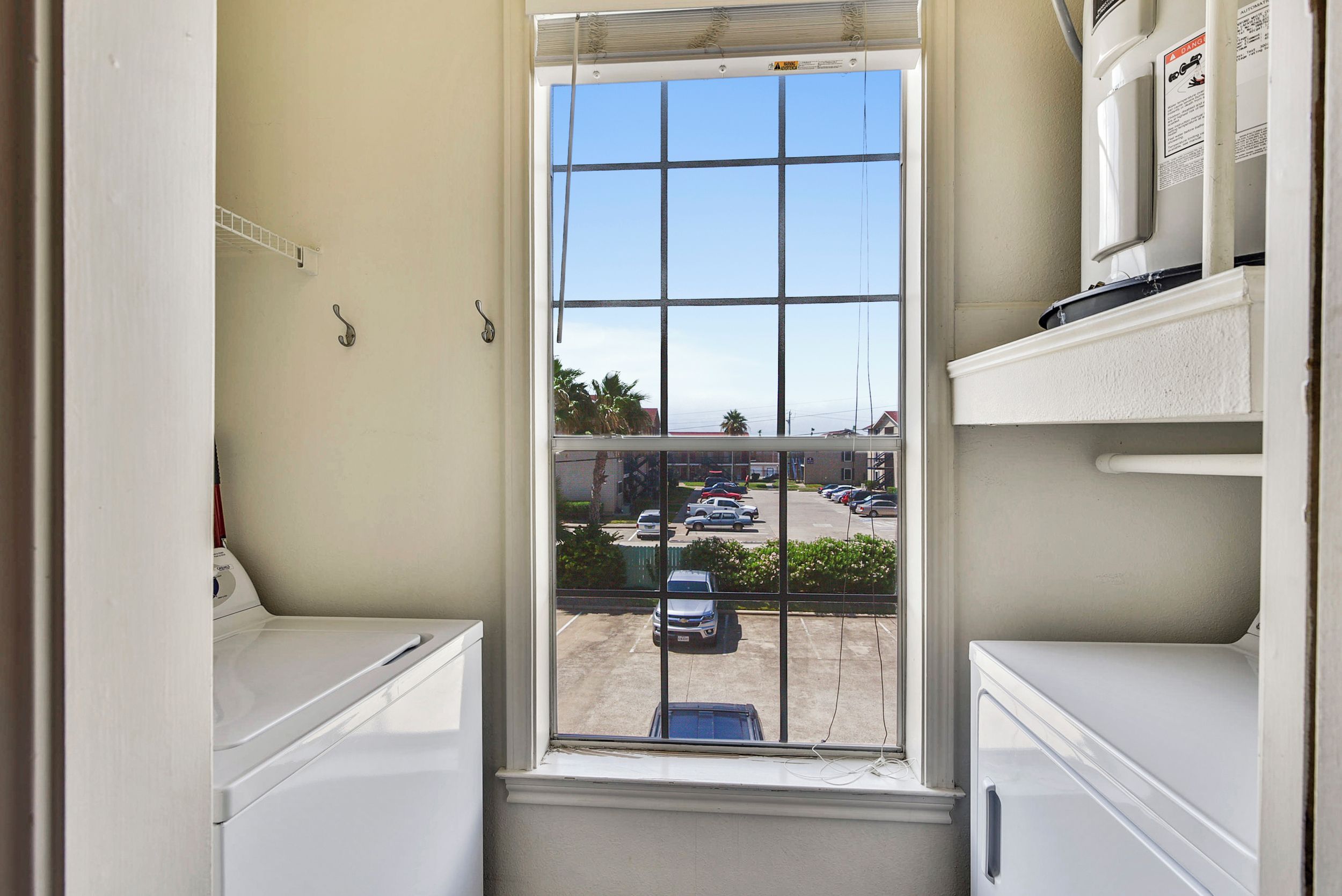 A laundry room with a large window overlooking a parking lot.