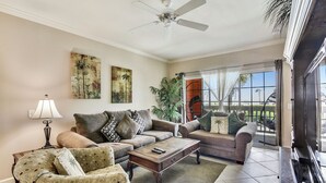A living room with two sofas, a coffee table, a lamp, and a ceiling fan. - Sea n' Swim by Ryson Vacation Rentals (Galveston)