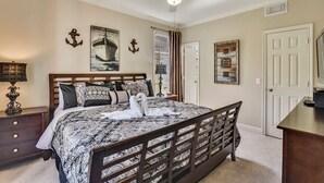 A bedroom with a bed, a ceiling fan, and a door. - Sea n' Swim by Ryson Vacation Rentals (Galveston)