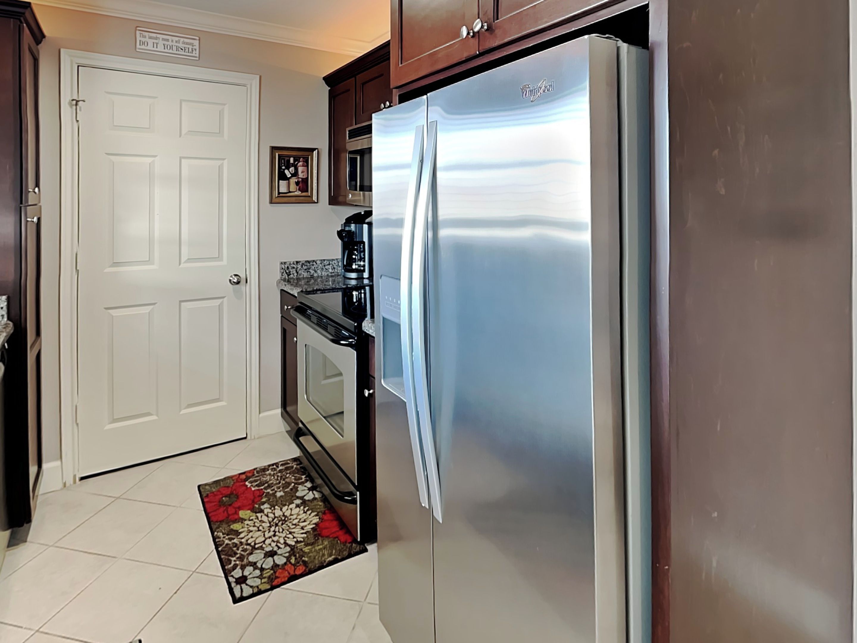 Una cocina con un refrigerador de acero inoxidable, horno, microondas y cafetera.