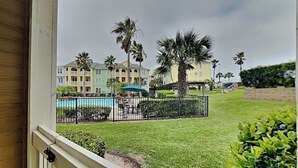 Vista de un hotel con piscina, palmeras y césped cuidado.