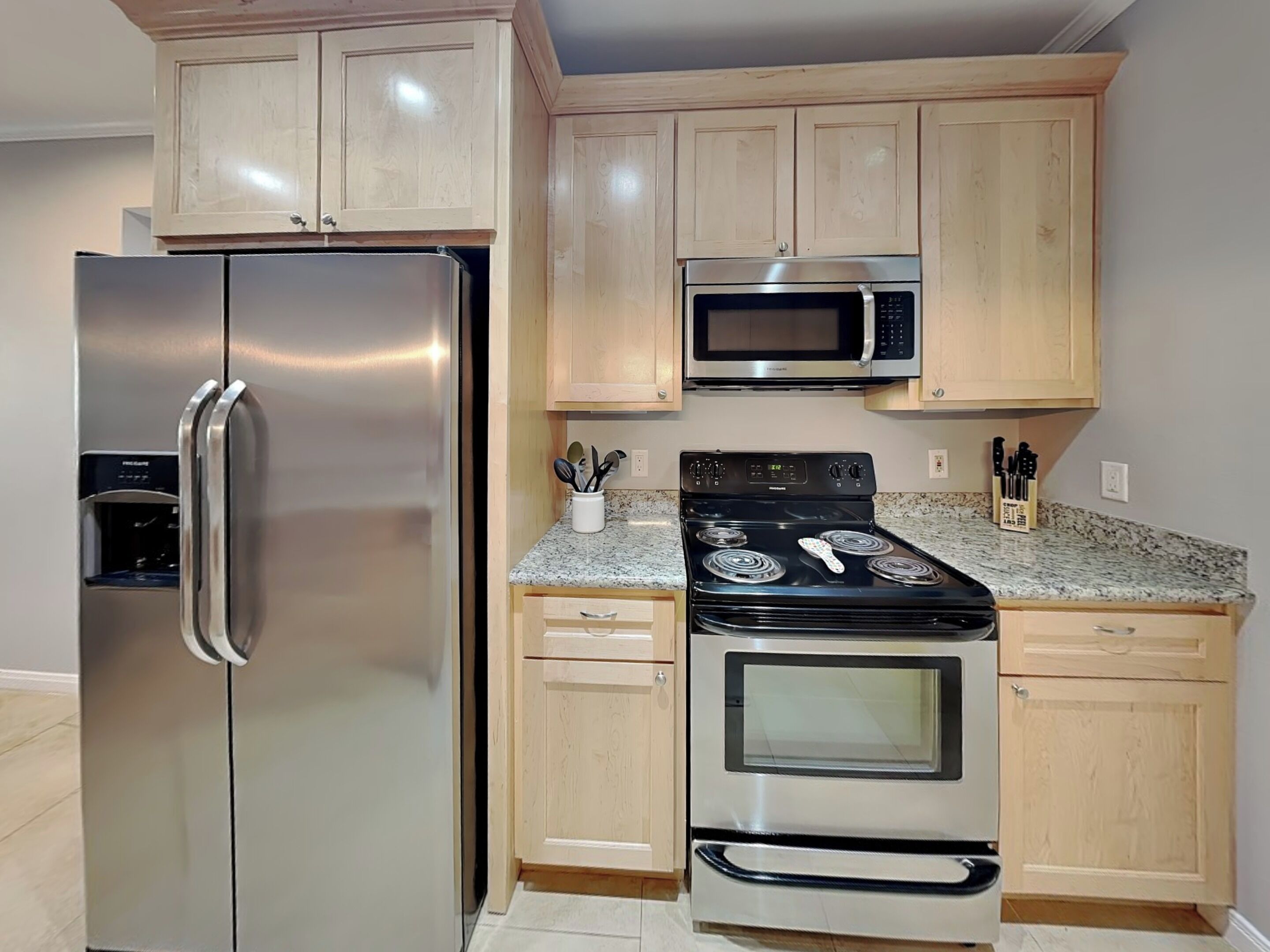 A kitchen with a stainless steel refrigerator, a microwave, and a stove.