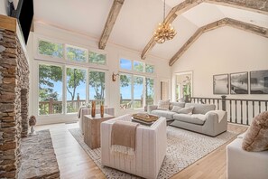 Relax in this airy living room with high ceilings and a large window set offering views of the outdoors.