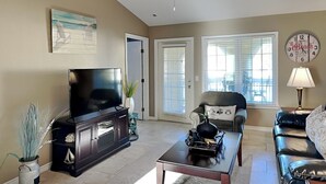 Ein Wohnzimmer mit Fernseher, Couchtisch, Sofa und Sessel.