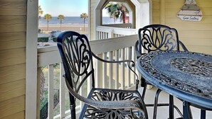 Ein Balkon mit Tisch und Stühlen, Blick auf den Strand, und ein Schild mit der Aufschrift 'Gone Sailing'.