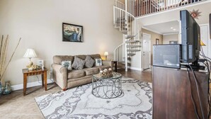 A living room with a sofa, coffee table, and TV stand. - The Regal Seagull by Ryson Vacation Rentals (Galveston)