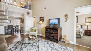 A spacious living room with a staircase, a television, and a dining area. - The Regal Seagull by Ryson Vacation Rentals (Galveston)