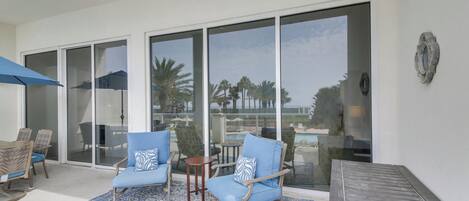 A modern outdoor seating area with two blue cushioned chairs, a small round table, and a blue patterned rug.