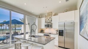 A modern kitchen with a large island, stainless steel appliances, and a view of the outdoors. - Beach Time by Ryson Vacation Rentals (Galveston)