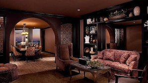 Ein luxuriöses Wohnzimmer mit einer Couch, Sesseln, einem Couchtisch und einem Essbereich mit einer Chandelieber.