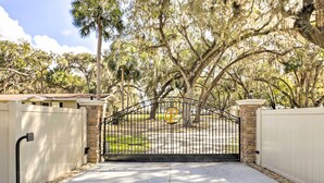 A gated driveway leading to a property with a stone wall and a metal gate. - < 1 Mi to Lake Weir: Quiet Summerfield Getaway (Summerfield)