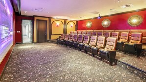 Un teatro con hileras de asientos cómodos, piso alfombrado y apliques decorativos en las paredes.