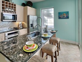 Una cocina con encimera de granito, electrodomésticos de acero inoxidable y ventana con vistas.