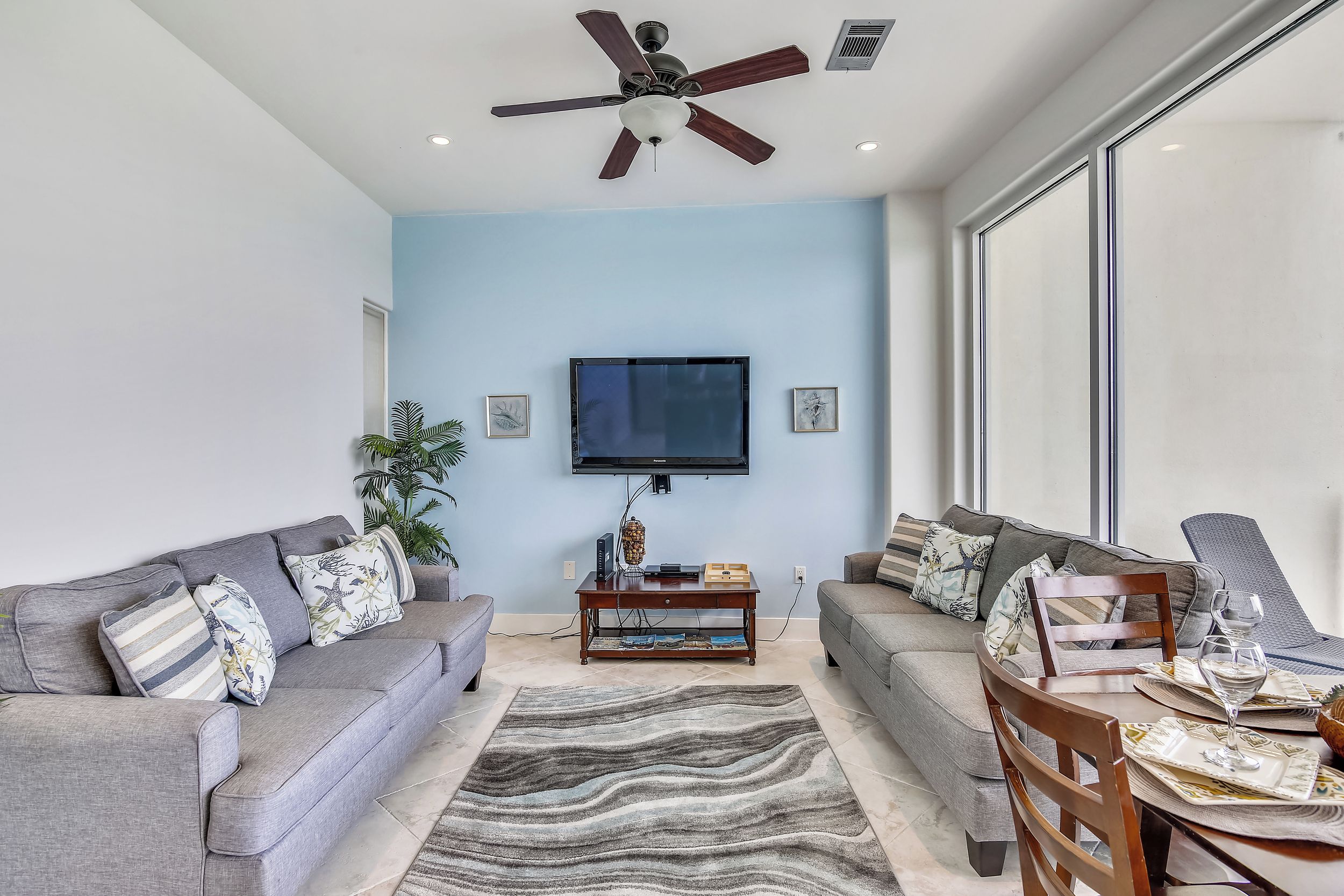 A modern living room with grey sofas, a coffee table, and a dining table set for two.