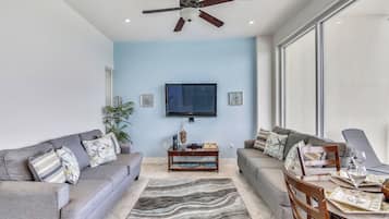 A modern living room with grey sofas, a coffee table, and a dining table set for two.