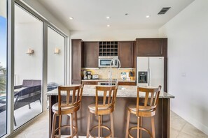 Una cocina moderna con una isla grande, taburetes de bar y vistas al exterior.