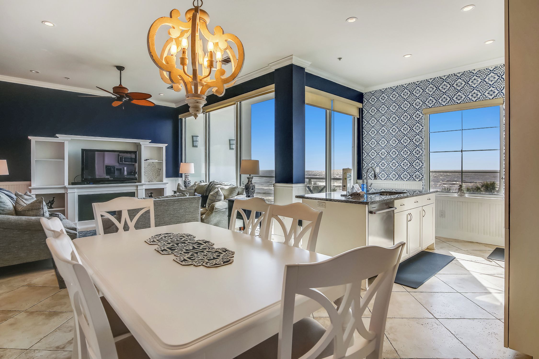 A modern kitchen with a dining area, large windows, and a view of the landscape.