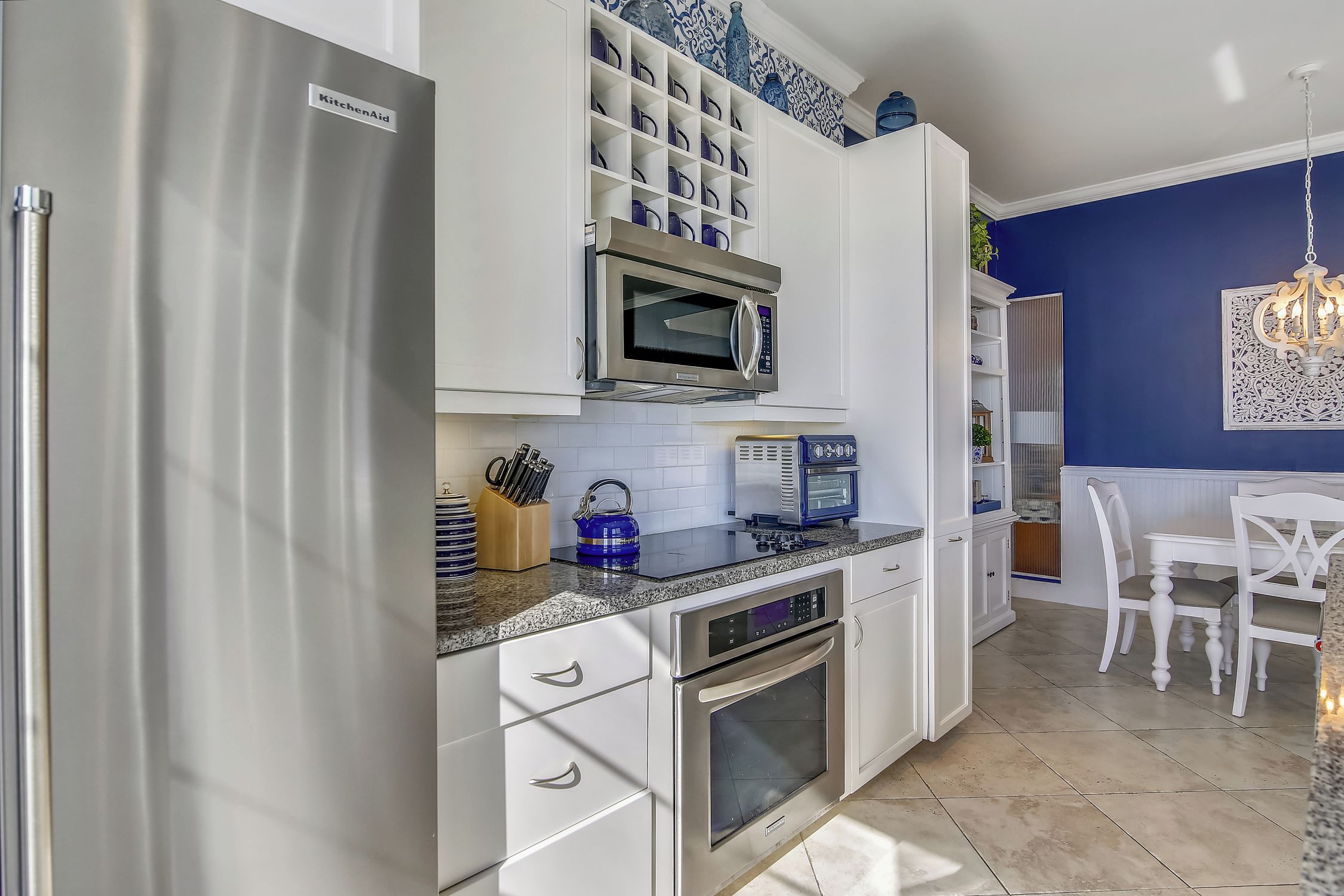 Una cocina moderna con armarios blancos, electrodomésticos de acero inoxidable y una pared de acento azul.