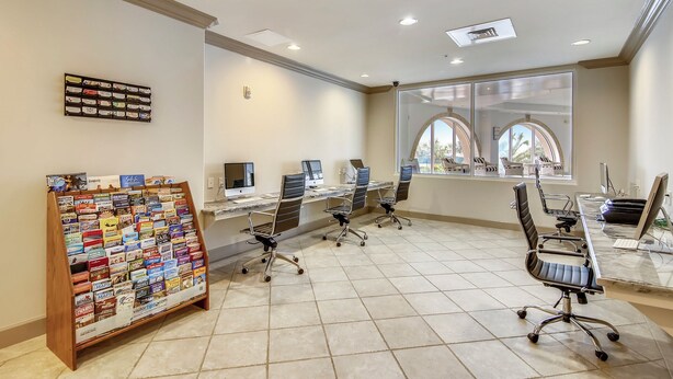 A modern office space with a bulletin board, multiple workstations, and large windows. - Precious Memories by Ryson Vacation Rentals (Galveston)