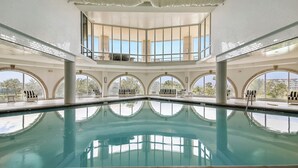 An indoor swimming pool with clear views of the outdoors, large windows, and a tiled ceiling. - Precious Memories by Ryson Vacation Rentals (Galveston)