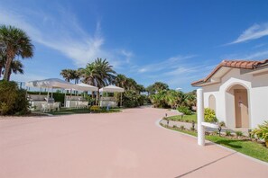 A resort with outdoor seating, palm trees, and a clear sky.