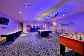 Enjoy games and entertainment in this room featuring a pool table, foosball table, billiards table, arcade machines, and a TV.