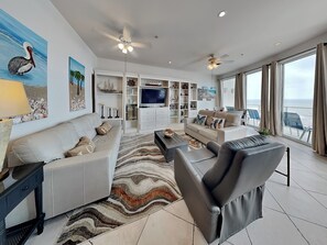 Una sala de estar moderna con un sofá, un sillón, televisor y vistas al mar.