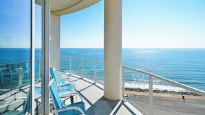 Ein Balkon mit Blick auf das Meer, ausgestattet mit einem Geländer und einigen Stühlen.