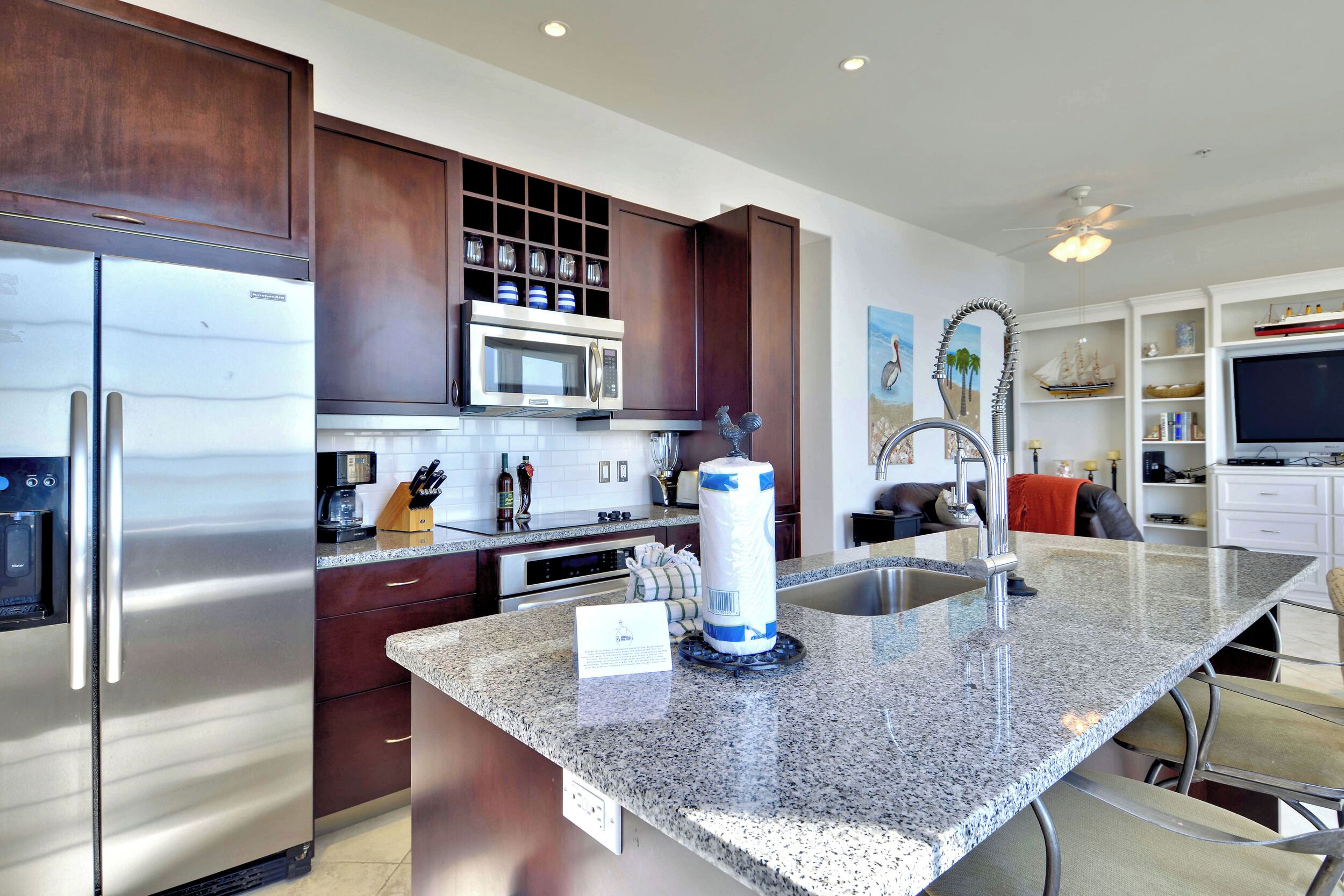 A modern kitchen with stainless steel appliances, granite countertops, and dark wooden cabinets.