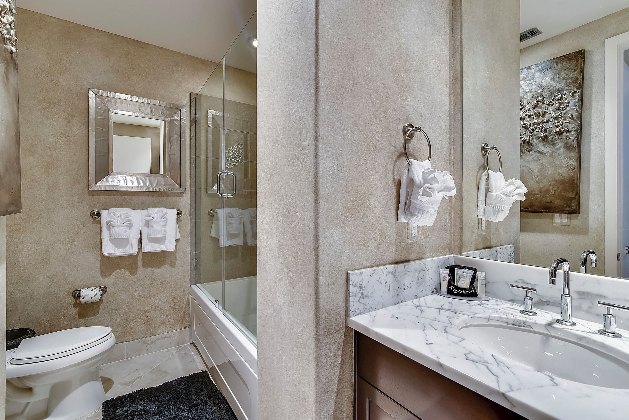 A modern bathroom with a large mirror, a bathtub, a toilet, and a sink.