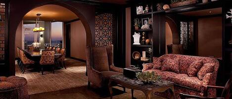 A luxurious living room with a sofa, armchairs, a coffee table, and a dining area with a chandelier.