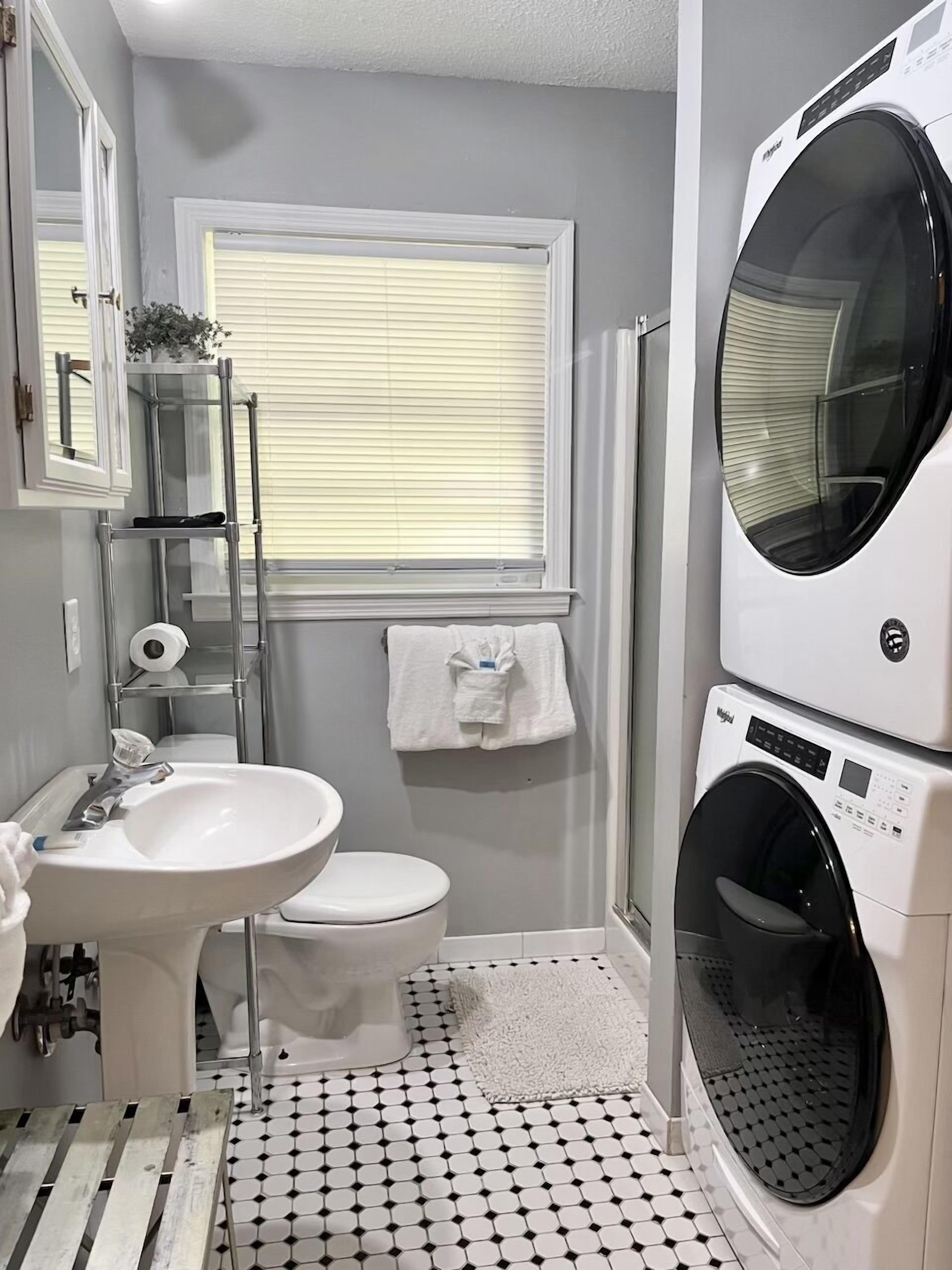 Une petite salle de bain comprenant un lavabo, des toilettes et un appareil combiné lave-linge et sèche-linge.