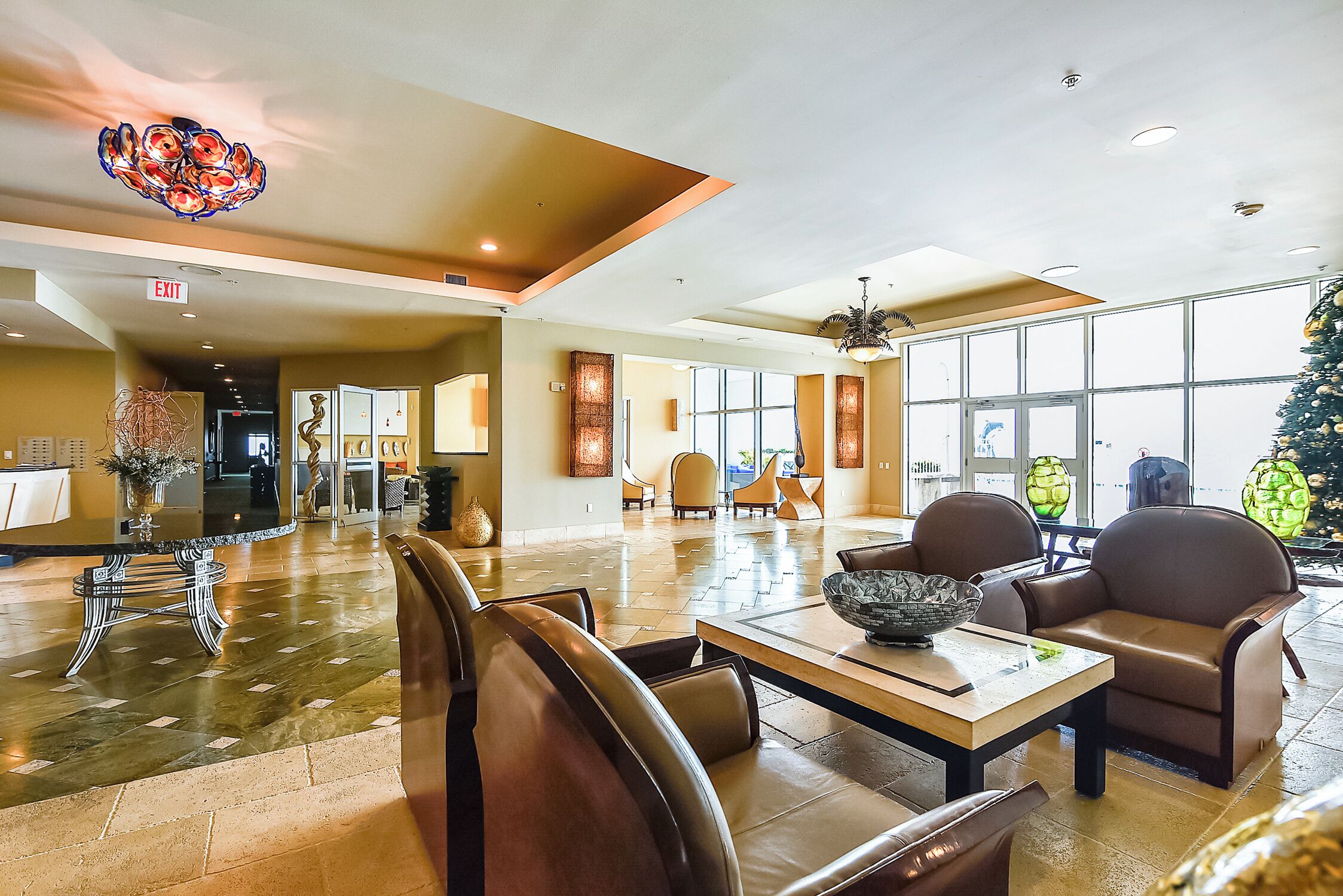A spacious lobby with a high ceiling, a central seating area, and large windows allowing natural light.