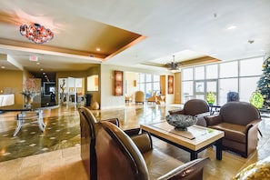A spacious lobby with a high ceiling, a central seating area, and large windows allowing natural light.