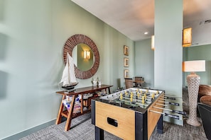 A room with a foosball table, a round mirror, and a small sailboat model.