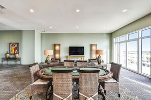 A conference room with a round table, wicker chairs, and a large window with a city view. - Emerald 1111 by Ryson Vacation Rentals (Galveston)