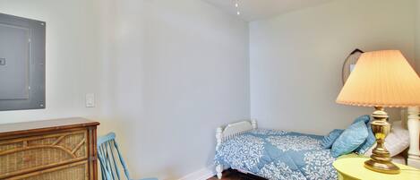 A bedroom with a bed, a chair, a dresser, a lamp, and a ceiling fan.