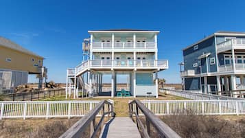 Un bâtiment situé en bord de mer, avec une promenade en bois qui mène à une zone abritée d’où l’on peut admirer l’océan.
