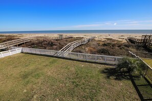 A beach view with a wooden boardwalk and white railings.