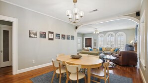A dining area with a round wooden table and chairs, a chandelier, and framed pictures on the wall. - Endless Summer by Ryson Vacation Rentals (Galveston)
