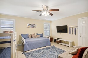 A bedroom with a bed, a ceiling fan, a TV, and a window. - Endless Summer by Ryson Vacation Rentals (Galveston)